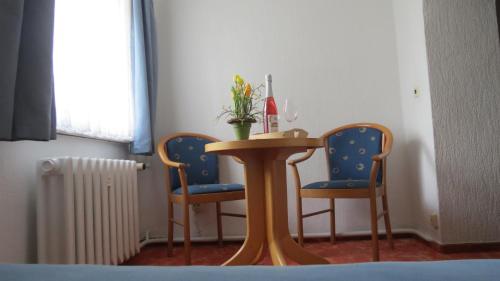 einen Tisch mit zwei Stühlen und eine Vase mit Blumen darauf in der Unterkunft Pension Waldhaus in Eibenstock