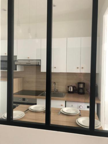 a kitchen with white cabinets and white plates on a counter at En hyper centre, Le Saint Aubin in Angers