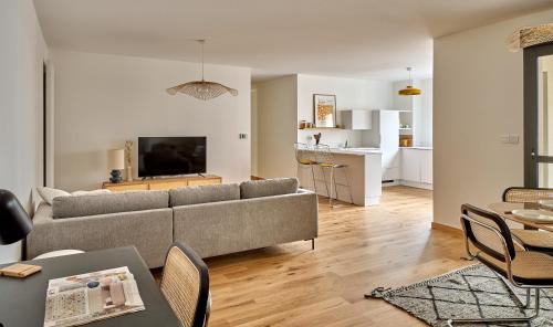 un salon avec un canapé et une table avec des chaises dans l'établissement Appart' Jeannette en Hyper centre ville avec balcon et Parking sous-terrain, by PRIMO C0NCIERGERIE, à Nevers