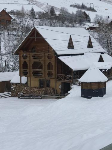 a log cabin with snow on the roof at Trembita готель in Yablunytsya