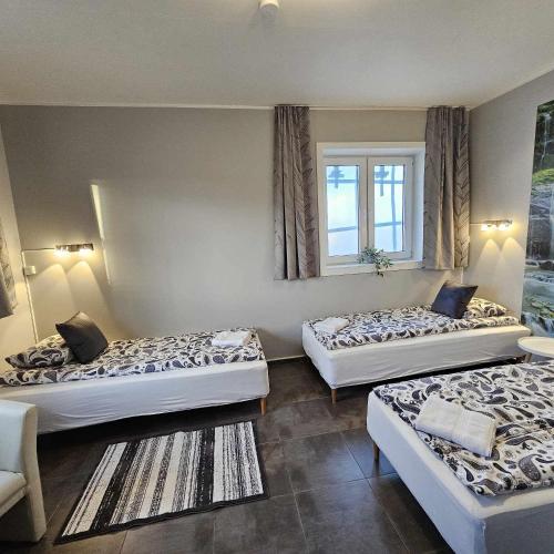 a room with three beds and a window at Guesthouse Kiljan in Blönduós