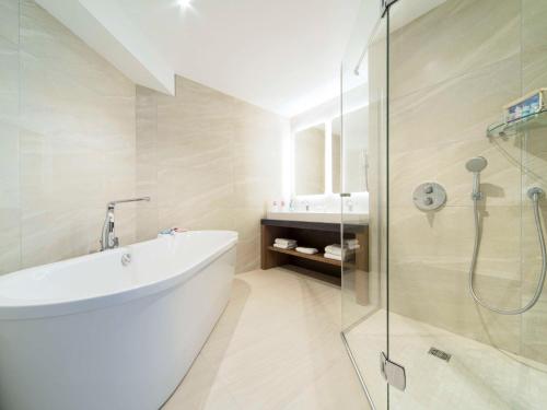 La salle de bains est pourvue d'une baignoire et d'une douche en verre. dans l'établissement ibis Styles La Rochelle Centre, à La Rochelle