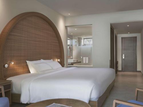 a bedroom with a large white bed and a mirror at Novotel Phu Quoc Resort in Phu Quoc