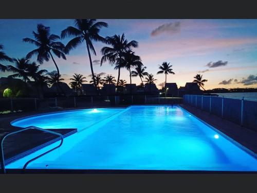 ein großer blauer Pool mit Palmen bei Sonnenuntergang in der Unterkunft DREAM ON THE BEACH in Baie Nettle