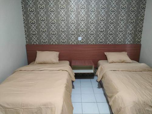 um quarto com duas camas e uma parede com papel de parede em WISMA AULIA 88 em Tembilahan
