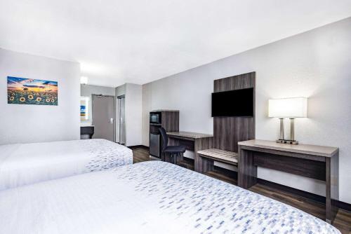 a hotel room with two beds and a desk at Wingate by Wyndham Wichita Airport in Wichita