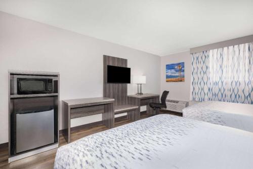 a hotel room with a bed a desk and a tv at Wingate by Wyndham Wichita Airport in Wichita