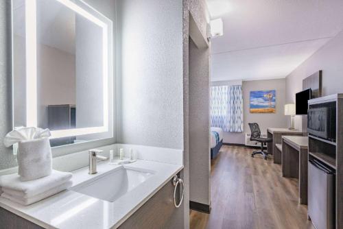 a white bathroom with a sink and a desk at Wingate by Wyndham Wichita Airport in Wichita