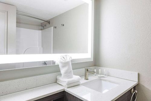 a white bathroom with a sink and a mirror at Wingate by Wyndham Wichita Airport in Wichita