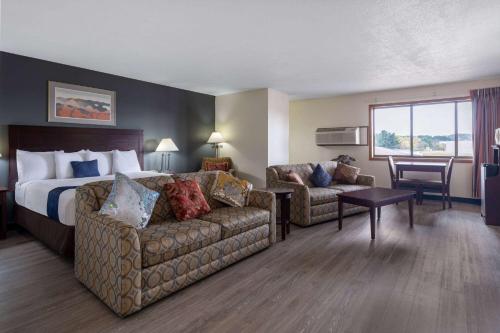 a hotel room with a bed and a couch at Travelodge by Wyndham Merrill in Merrill