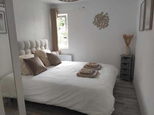 a bedroom with a large white bed with a mirror at Le Petit Gite de la Roseraie in Quiberville