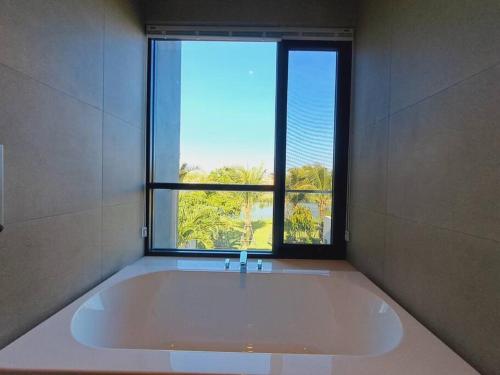 un bagno con ampia vasca e finestra di Sanctuary Ho Tram Villa a Ho Tram