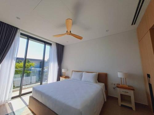 - une chambre avec un grand lit et une grande fenêtre dans l'établissement Sanctuary Ho Tram Villa, à Ho Tram