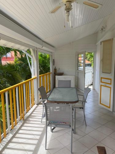 a porch with a table and chairs on it at Bungalow Belfond Plage Pointe Marin in Sainte-Anne