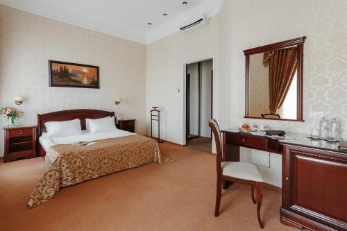 a bedroom with a bed and a desk and a mirror at Royal Street Hotel in Odesa