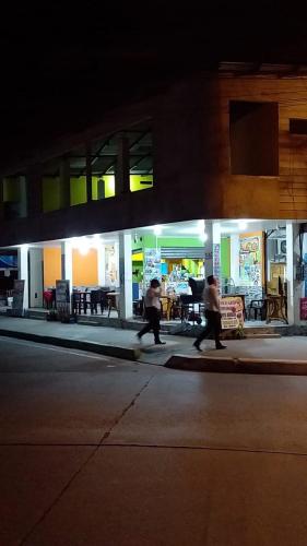 duas pessoas a andar numa rua à noite em La esquina del capitán em San Vicente