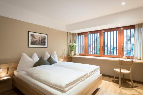 a bedroom with a large white bed and windows at Hotel Johann Lauterach in Lauterach