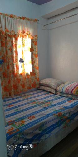 Ce lit se trouve dans un dortoir doté d'une fenêtre et d'un couvre-lit. dans l'établissement Blue Haven Unit 1, à Baguio