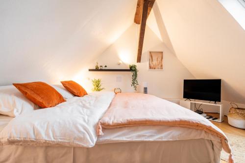 une chambre avec un grand lit blanc avec des oreillers orange dans l'établissement Nid cosy au centre ville, vue magique cathédrale, à Strasbourg