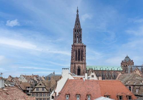 une grande tour d'horloge dans une ville avec des toits dans l'établissement Nid cosy au centre ville, vue magique cathédrale, à Strasbourg