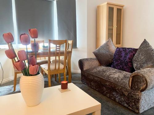 een woonkamer met een bank en een tafel met bloemen in een vaas bij Sedgefield luxury Apartments. in Sedgefield