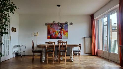 a dining room table with chairs and a painting on the wall at Bd du Lycée-Rue d'Issy in Vanves