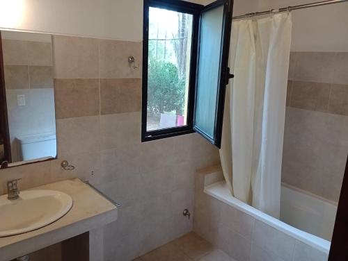 een badkamer met een wastafel, een bad en een raam bij PINAR DEL SOL I y II in La Paloma