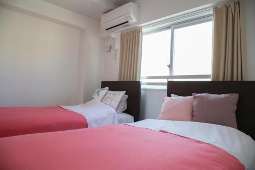 宇流麻的住宿－Guest room WES - Vacation STAY 49860v，粉红色和白色的客房内的两张床