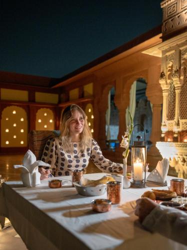 a woman sitting at a table in a restaurant at Surpura Bagh - A Luxury Boutique Resort in Jodhpur