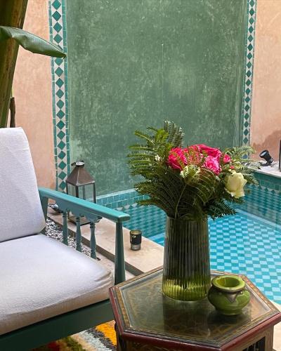 a vase with flowers on a table next to a chair at RIAD DAR NAOMI in Marrakech