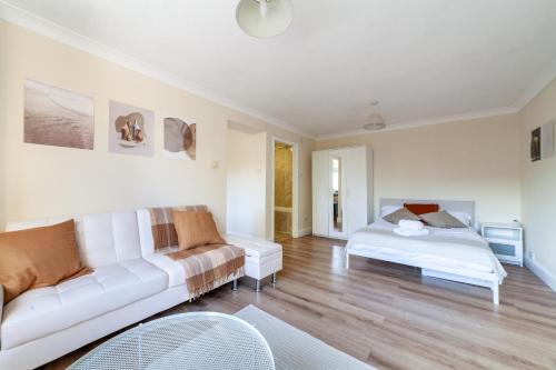 un soggiorno con divano bianco e letto di Lovely Studio Flat in Wimbledon w/ Free Parking a Londra