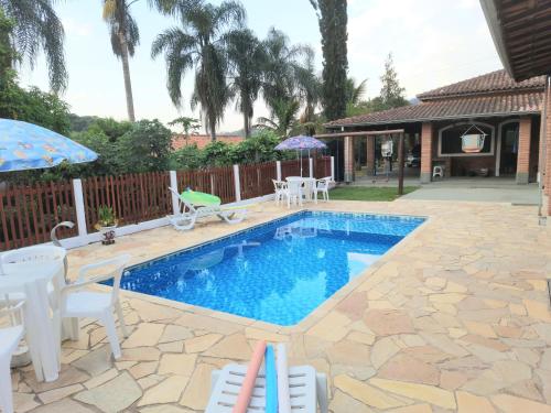 a swimming pool with white chairs and an umbrella at Chácara Vicente Gazzi in Socorro