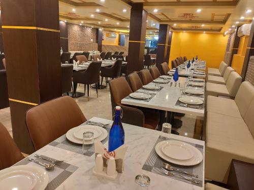 a dining room with long tables with plates and a blue bottle at Royal View Residency in Bodh Gaya