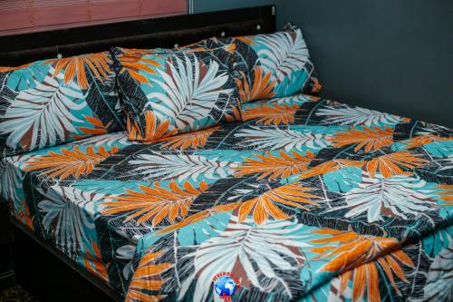 een bed met een kleurrijk dekbed met tropische bladeren bij JEVENOM HOTEL in Ibafo