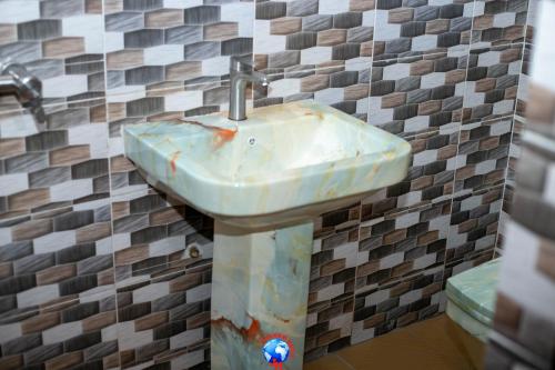 een badkamer met een wastafel in een betegelde muur bij JEVENOM HOTEL in Ibafo