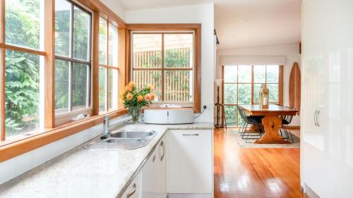 a kitchen with a sink and windows and a table at Rosemary Cottage in Cape Schanck