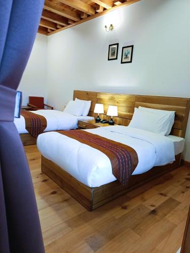 Duas camas grandes num quarto com pisos em madeira em Jagathang Village Inn em Paro