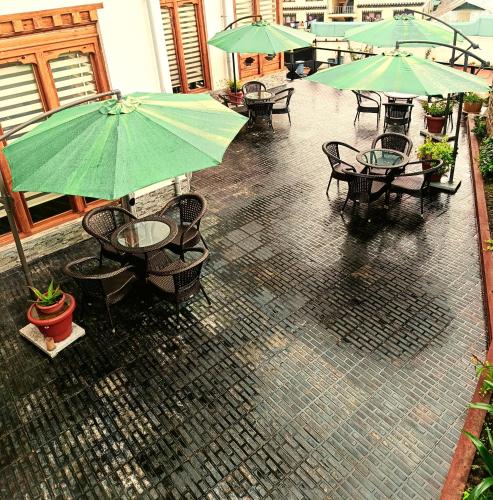 um pátio exterior com mesas e guarda-sóis na chuva em Jagathang Village Inn em Paro