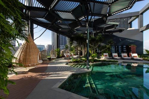 吉隆坡的住宿－Hotel Indigo Kuala Lumpur on the Park, an IHG Hotel，一座带遮阳篷的建筑屋顶上的游泳池