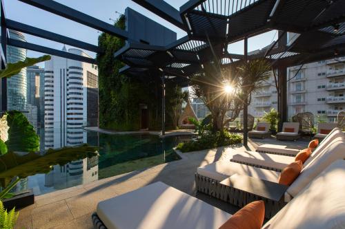Hotel Indigo Kuala Lumpur on the Park, an IHG Hotel في كوالالمبور: سطح الفندق مع كراسي صالة ومسبح