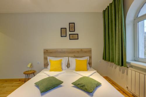 a bedroom with a white bed with yellow and green pillows at People Guest House in Bishkek