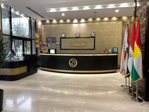 a hotel lobby with a reception desk and flags at Jouhayna Hotel&Suite in Erbil