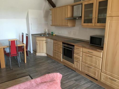 a kitchen with wooden cabinets and a table with red chairs at Maisonette Wohnung am Hänferdorf in Bühl