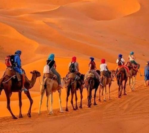 a group of people riding camels in the desert at Merzouga luxurious Camps in Merzouga