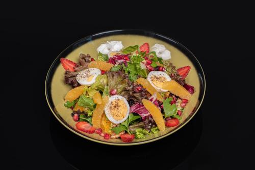a bowl of salad with fruit on a black table at Centro Al Manhal by Rotana in Abu Dhabi