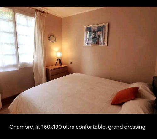 Schlafzimmer mit einem weißen Bett und einem roten Kissen in der Unterkunft Le bruit des vagues à Trouville sur mer in Trouville-sur-Mer