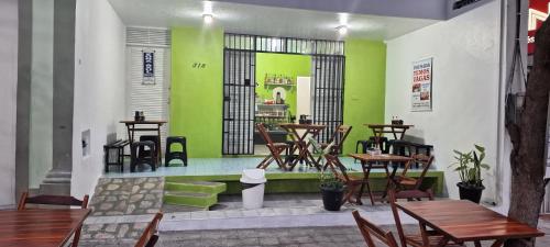 un restaurante con paredes verdes, mesas de madera y sillas en Pousada Point da Nanda en Juazeiro do Norte