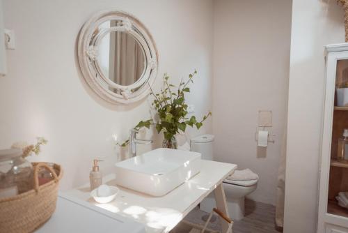 Baño blanco con lavabo y espejo en La Buena Sombra en Alicante