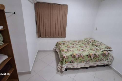 Apartamento top central في Pau dos Ferros: سرير في غرفة بيضاء مع بطانية عليه