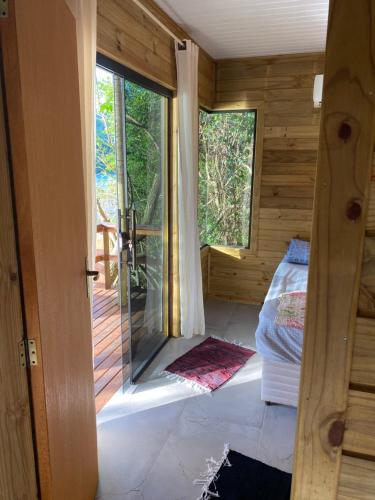 a room with a door open to a bedroom with a porch at Recanto Nativos in Garopaba